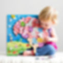 A blonde child is playing with a wooden logic game.