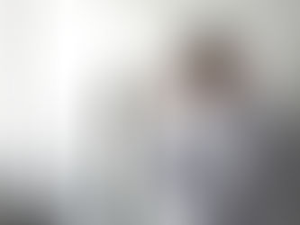 stressed looking man leans against wall, taking off his glasses.