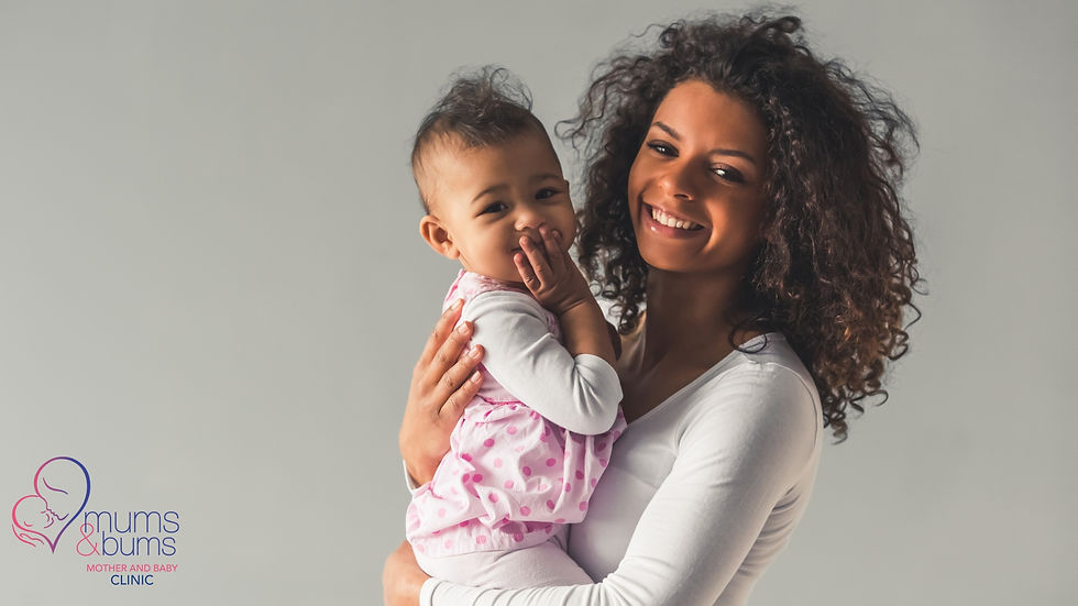 A smiling woman holding an older baby.