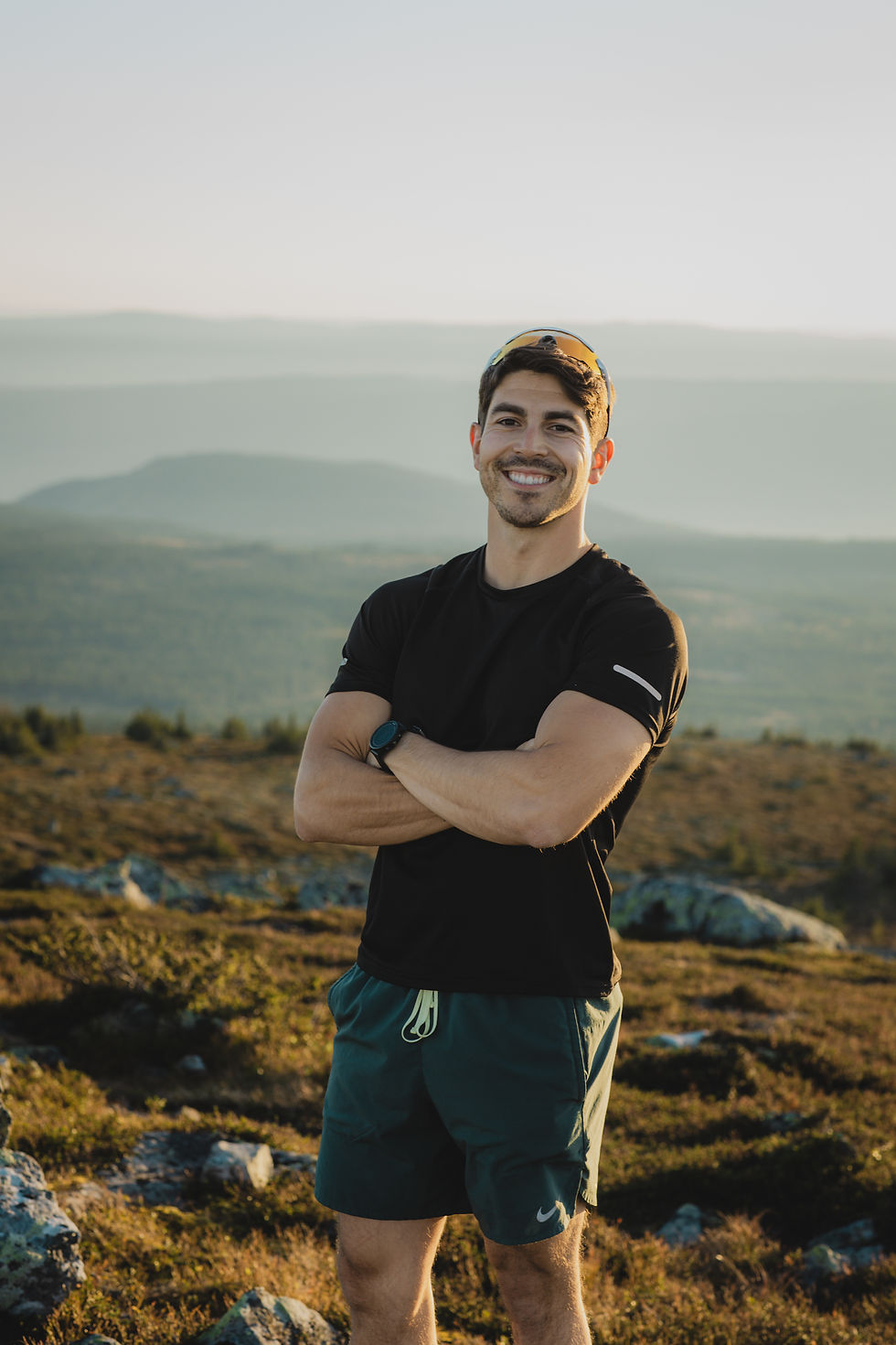 Ryan Toney smiling outdoors in athletic gear, standing on a mountain trail during sunset