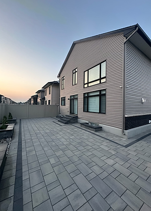 Geometric stone walkway installation with dark borders leading to a brick house.
