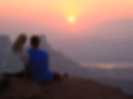 Two people watching the sun rise over Moab