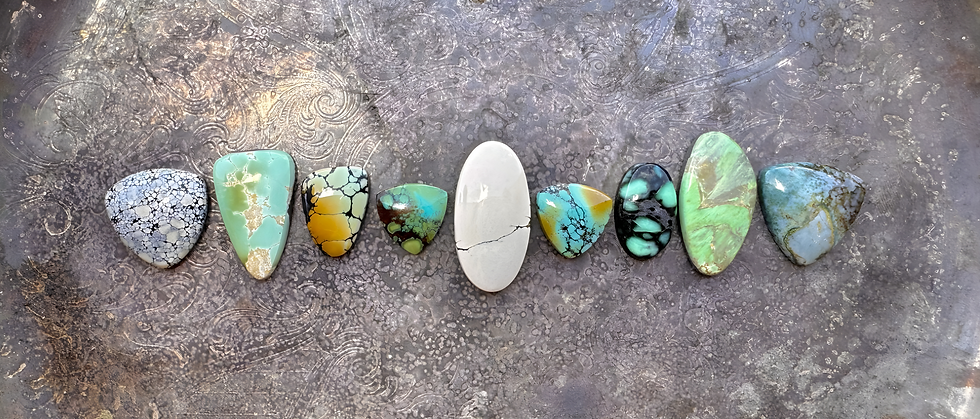 various stones including turquoise, jasper, and variscite laying on a detailed sterling silver tray