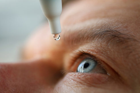 An elderly man applying HYLO® eye drops to his eyes, and the drop is about to be released from the bottle.