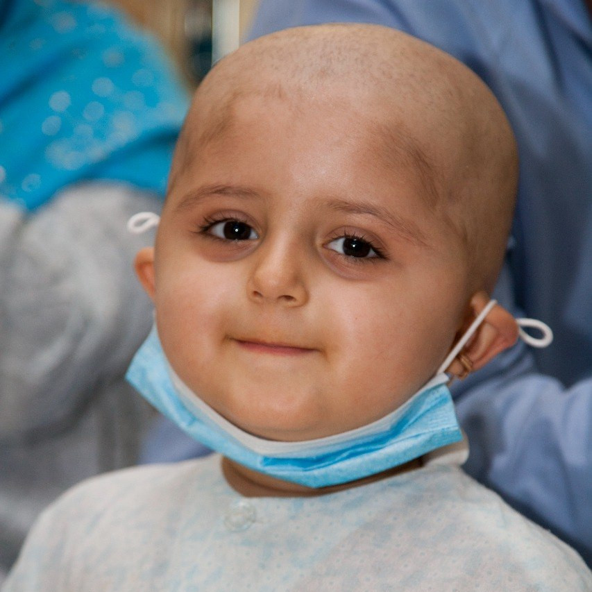 Smiling child with a face mask to support children with cancer