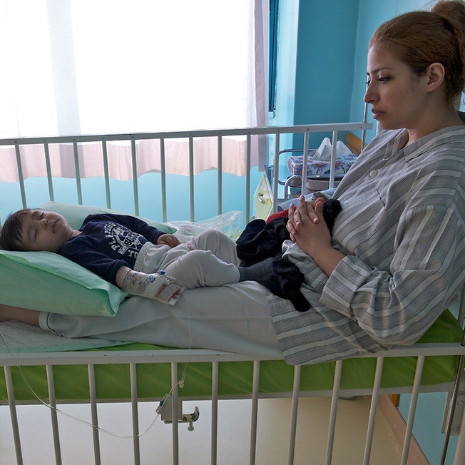 Mother staying by her sick child in a hospital bed.