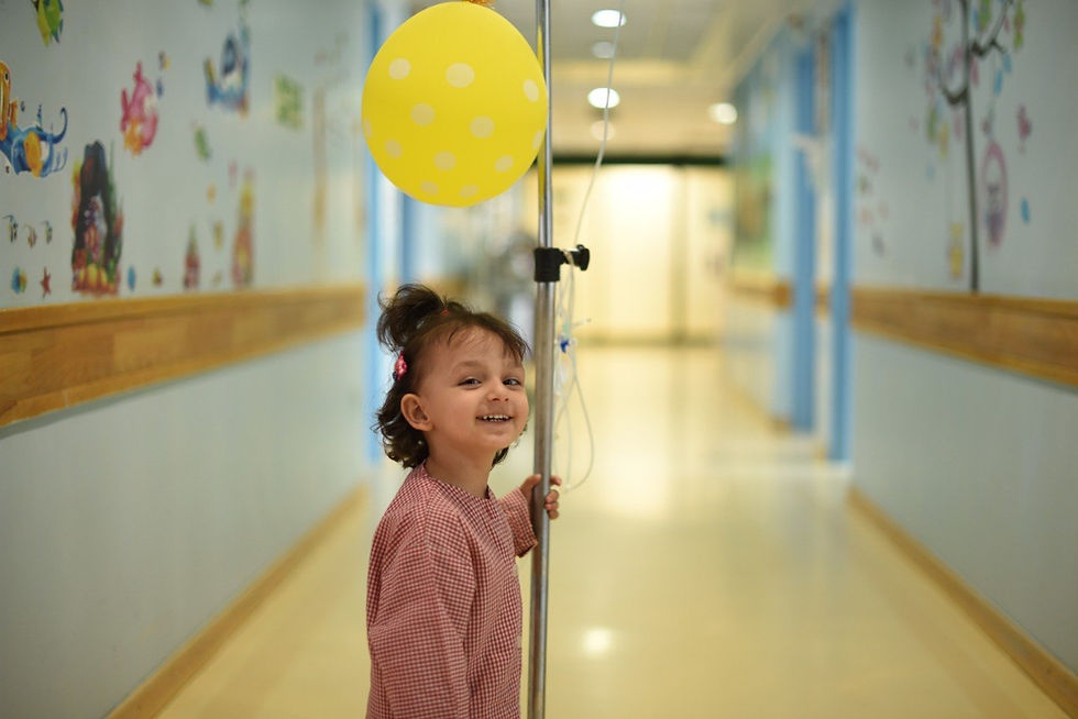Smiling girl with IV pole to support children with cancer
