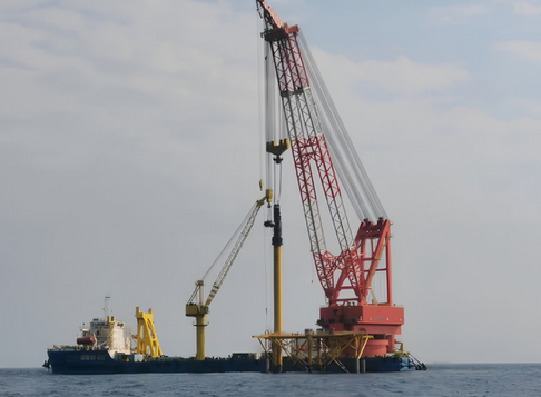 Floating crane mounted on a barge lifting heavy cargo in a harbor.