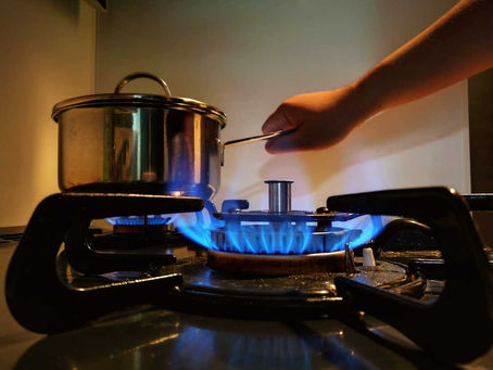 A hand putting a pot on a lighted gas stove