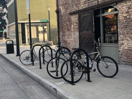 A row of bike racks on a footpath, with bikes attached to some
