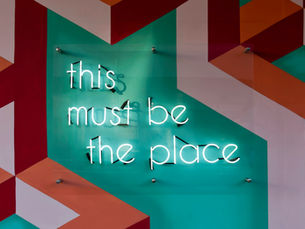 Neon sign on patterned wall - sign reads this must be the place