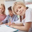 Close up of a cute little girl smiling to the camera while drawing at art class with her f