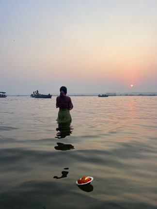 A woman prays at sunrise with a floating flower