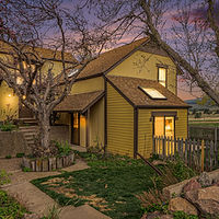 Yellow house with warm lights and trees evening view. Crisafulli Team