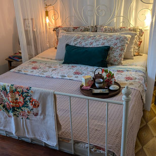 Casa OZ-Shabit after the experiential design intervention: see through bed canopy, layered and textural bed linens, and welcoming kit on bed with vintage textile detail and wooden bench.