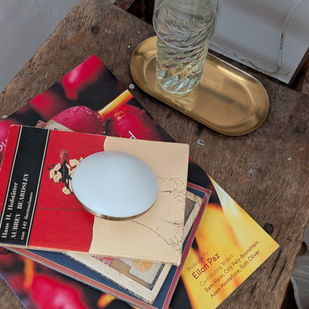 Mesa auxiliar de madera con botella de agua, libros y objeto aromático, preparada como punto de confort junto a la cama.