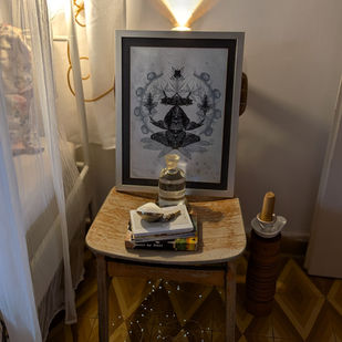 Mesa de noche de madera con botella de agua, libros y objeto aromático, acompañada por libros y luz ambiental cálida en Casa Razy.