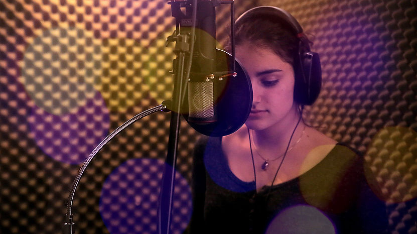 A Young female singer in a vocal booth.