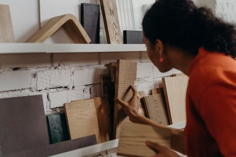 A person examining wood samples on a shelf filled with different boards and

materials