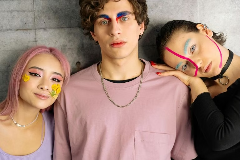 Three people with creative face paint and expressive makeup posing together to celebrate individuality and artistic expression.
