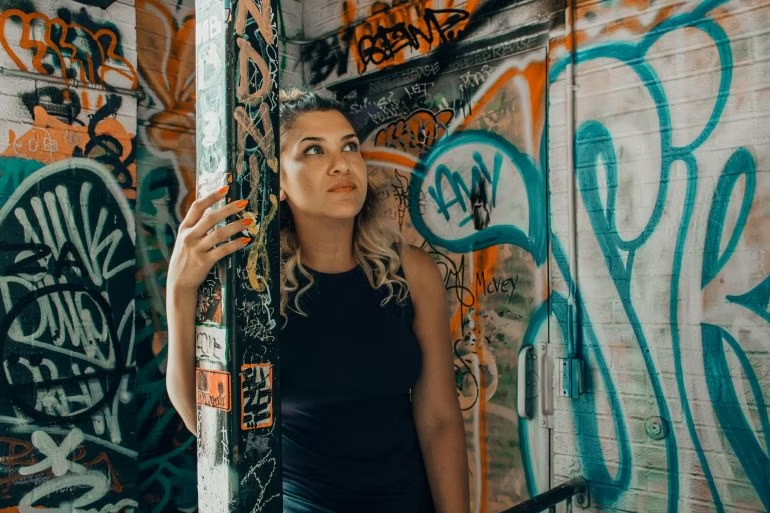 Woman standing in a colorful alley filled with graffiti, surrounded by bold street art  and creative expression.