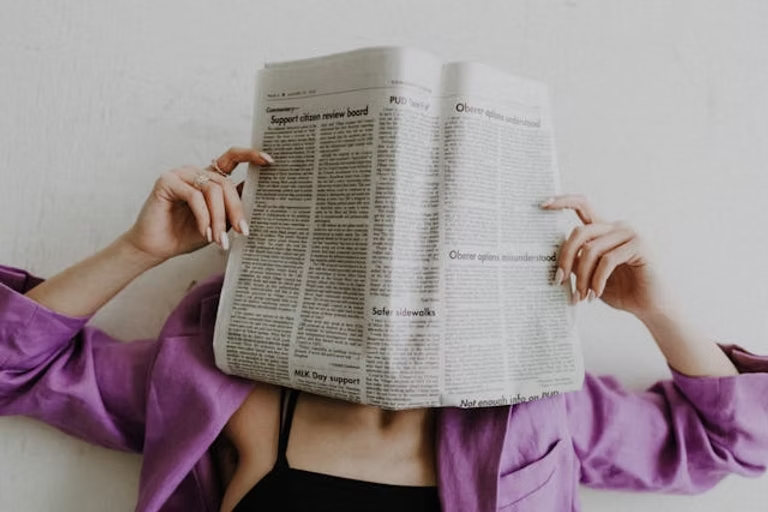A girl covering her face with a newspaper