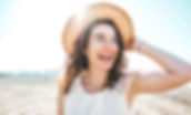 Femme souriante sur la plage. Éprouve une paix intérieure et se sent en pleine forme.