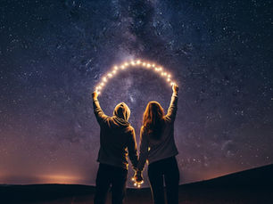 Twee figuren die samen een boog van licht/sterren vasthouden onder de Melkweg, als metafoor voor de spirituele verbondenheid en de collectieve evolutie van het menselijk bewustzijn.