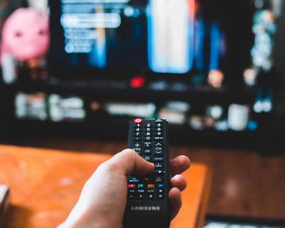 Hand holding Samsung remote pointing at TV with 