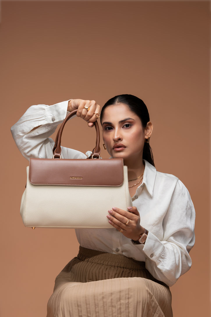 Close-up of the Miraggio handbag styled with a tan pleated skirt in a high-fashion advertising shoot.