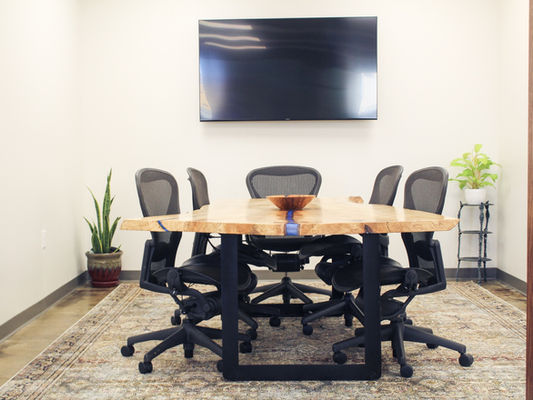 Conference room with a wooden table, office chairs, and wall-mounted TV