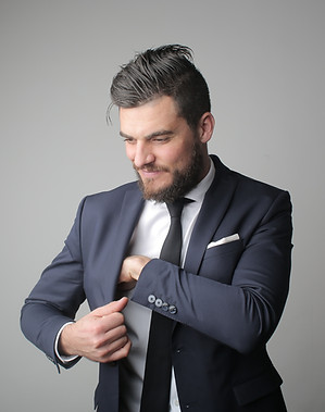 man-in-blue-suit-standing-near-gray-wall