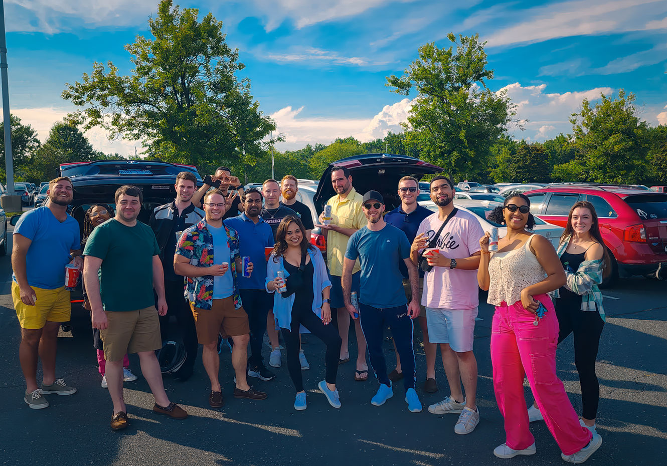 Group photo taken outdoors on a sunny day with trees and a blue sky in the background.