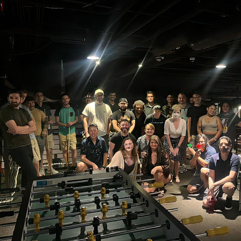 Group playing foosball and interacting at a lively indoor gathering.