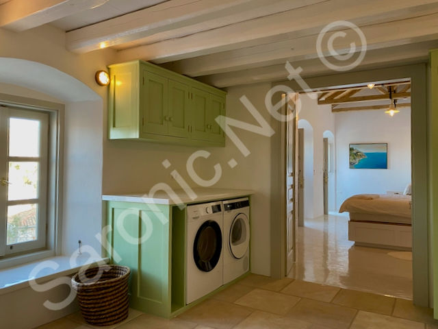 Off the main bedroom this en suite includes a useful laundry area with washer, dryer and built in storage units in sage green.