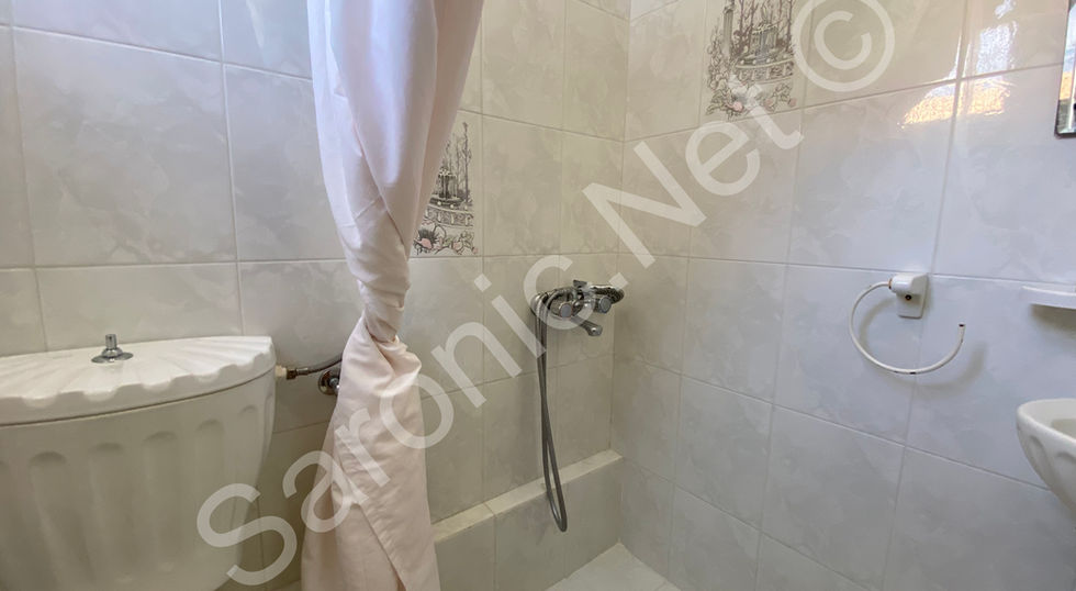 Fully tiled en suite with a shower and attractive white sink and lavatory suite.