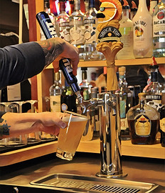 A bartender operating a beer tap, filling a pint, at a Grampy's Nevada location.