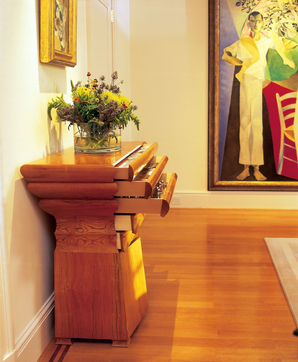 A bespoke cutlery cabinet by John Makepeace with drawers open and vase of flowers on top.
