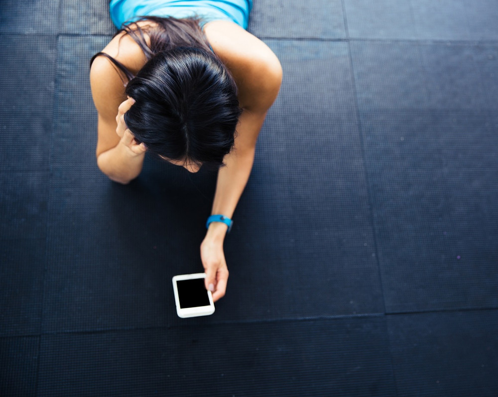 Woman lying on mat looking at iPhone