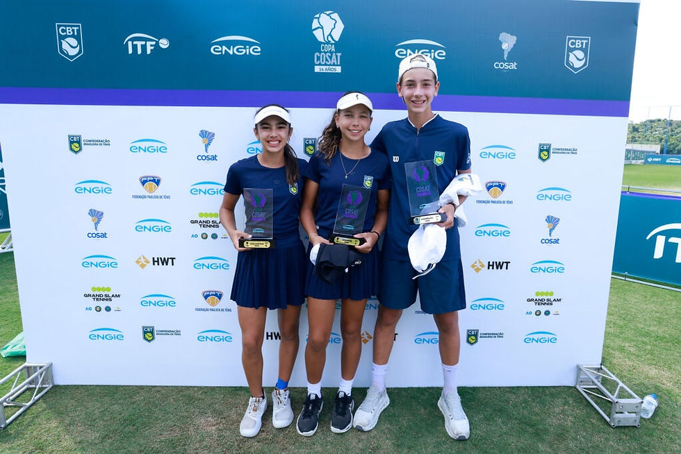 Três jovens sorriem com troféus em frente a um banner de tênis com logotipos CBT, ITF, ENGIE. Estão em uniforme azul em um campo de grama.
