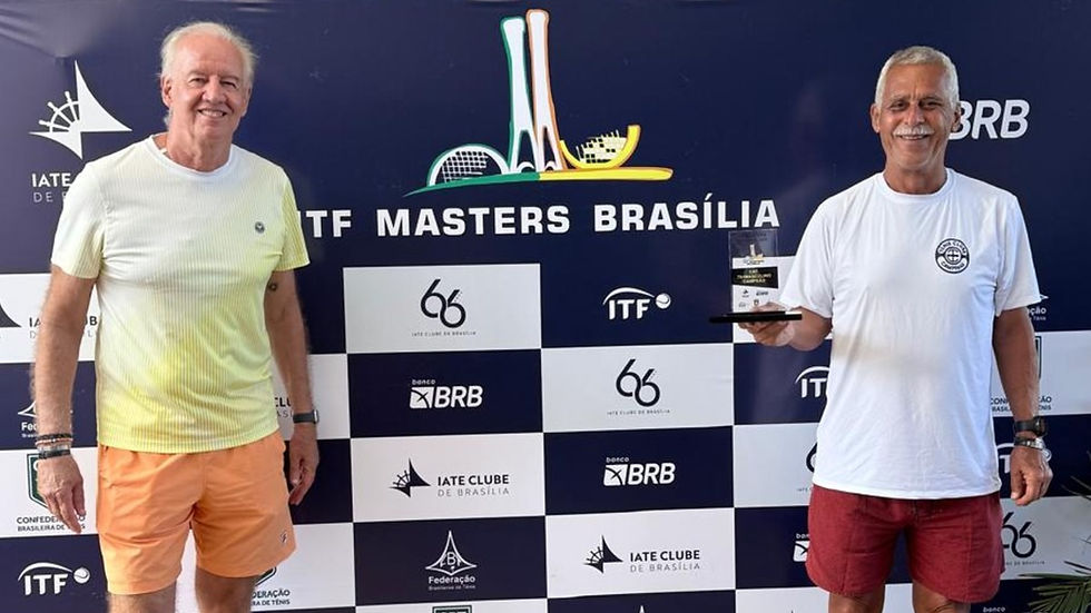 Dois homens sorrindo, um segurando um troféu. Fundo com logotipos e texto "ITF Masters Brasília". Camisetas brancas e shorts coloridos.