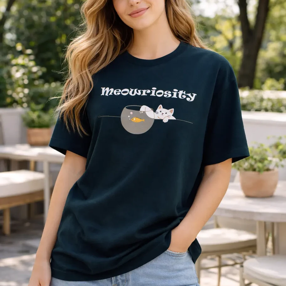 Young woman poses in Meowriosity t-shirt and denim shorts on patio.