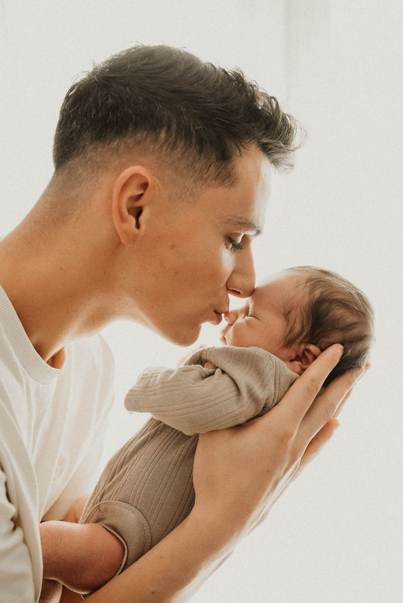 Papa donnant un bisou à son bébé dans ses mains.