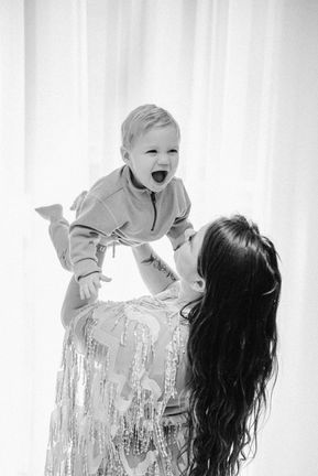 Maman faisant l’avion avec son enfant, photo en noir et blanc.