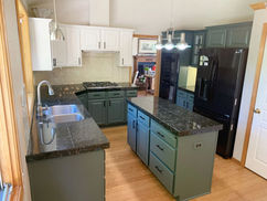 Modern kitchen with green cabinets and dark countertops