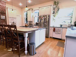 Modern kitchen with island, wooden stools, and brick wall.