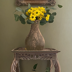 Yellow flowers in a vase on an ornate wooden side table