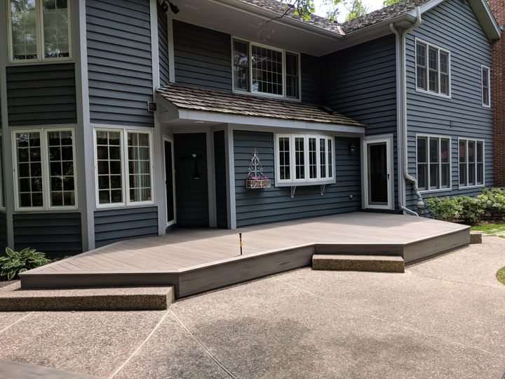Completed TimberTech Silver Maple porch with two steps and patio transition in Northbrook IL