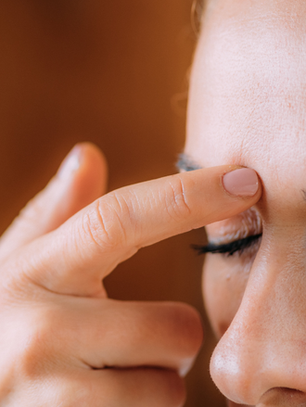 A close-up of a woman tapping gently on her face, demonstrating Emotional Freedom Techniques (EFT) for healing and self-connection.