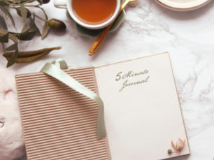 Flat lay of a cup of tea, biscuit, and 5 Minute Journal — symbolising reflection and checking in with yourself.
